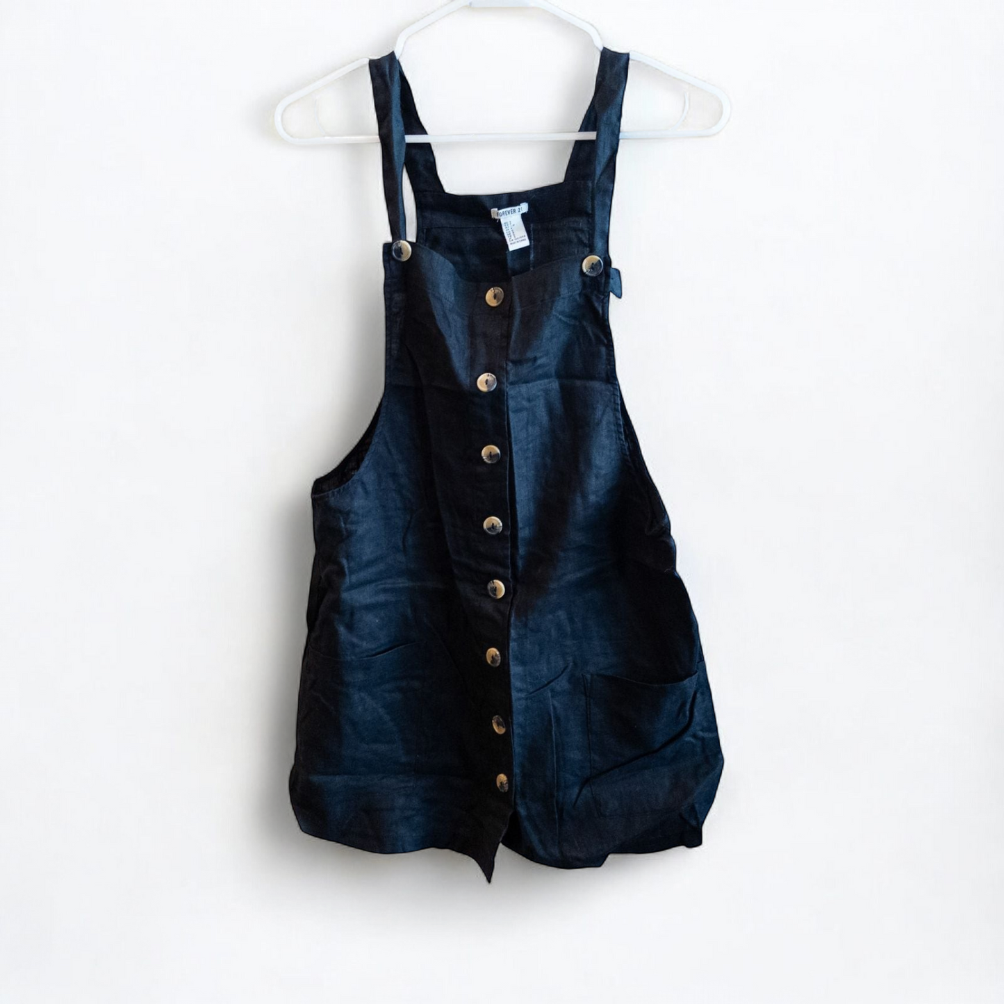 Forever 21 black linen dress with button front and adjustable straps hanging on a white hanger