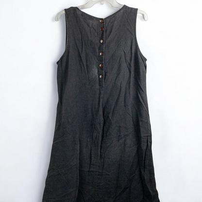 Sweet Jessie black denim long sleeveless dress with front decorative buttons and back button closure hanging on a hanger in front of a bookshelf and mirror image 3