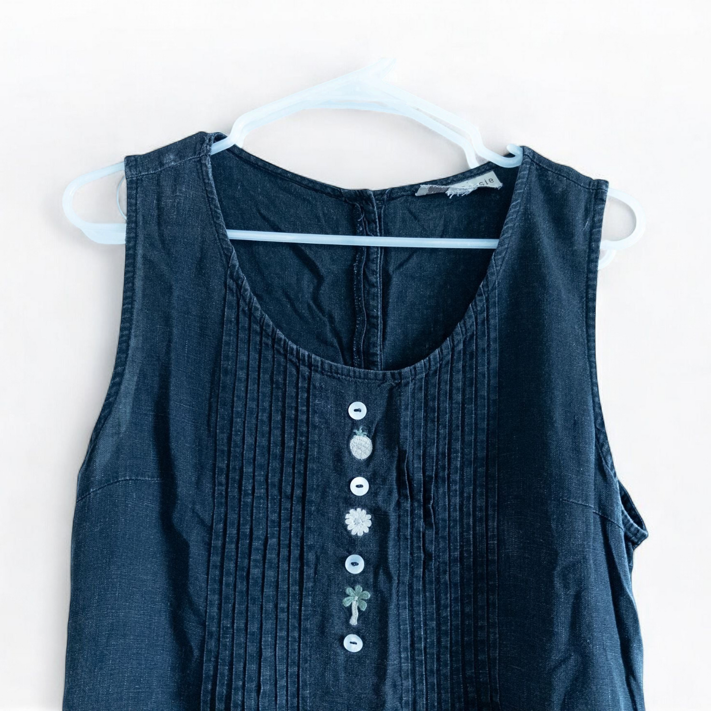 Sweet Jessie black denim long sleeveless dress with front decorative buttons and back button closure hanging on a hanger in front of a bookshelf and mirror image 4