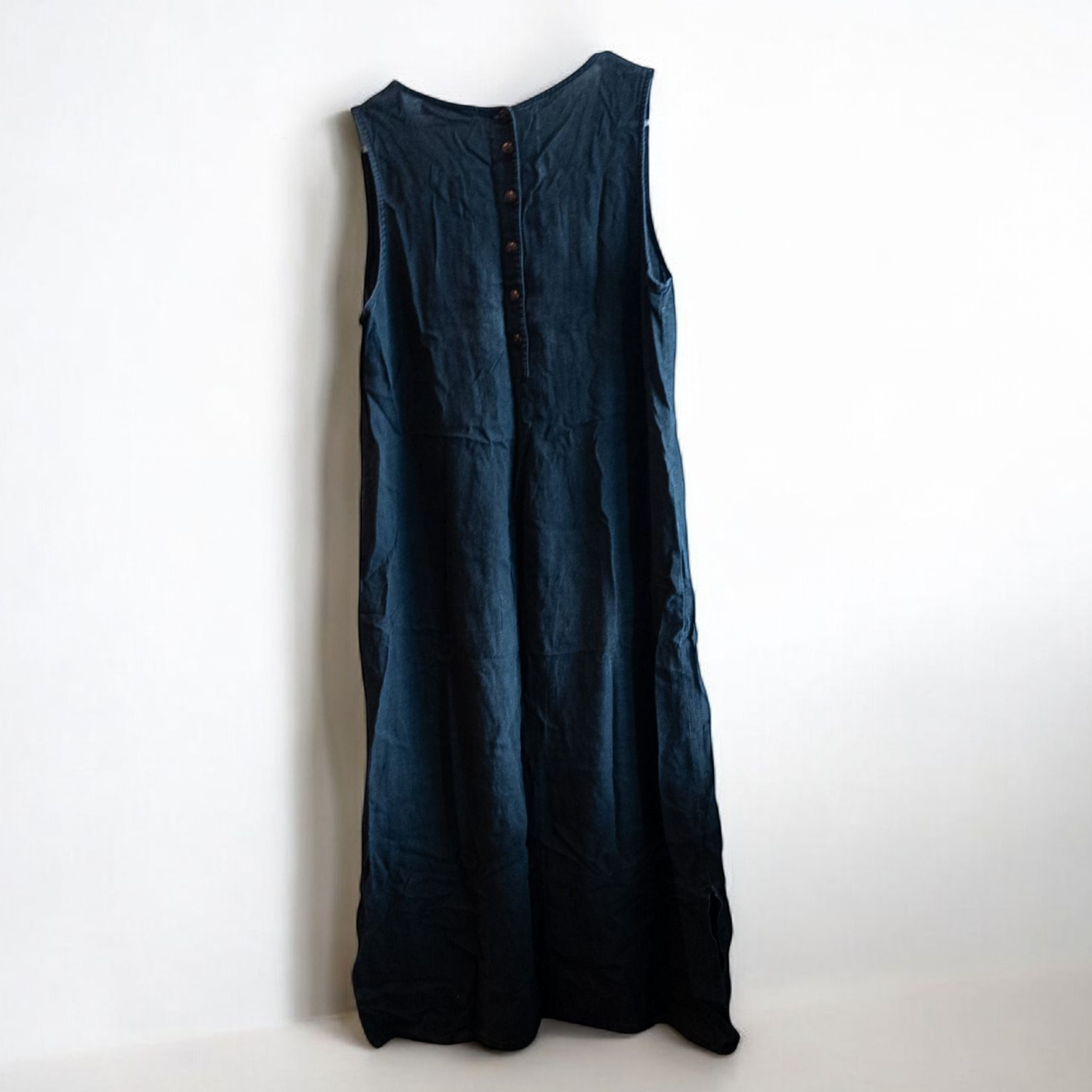 Sweet Jessie black denim long sleeveless dress with front decorative buttons and back button closure hanging on a hanger in front of a bookshelf and mirror image 7