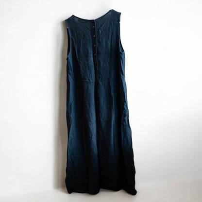 Sweet Jessie black denim long sleeveless dress with front decorative buttons and back button closure hanging on a hanger in front of a bookshelf and mirror image 7