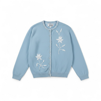 Stewarts pastel blue vintage cardigan with white bead floral embellishments and pearl buttons on a hanger front on white muslin photography backdrop