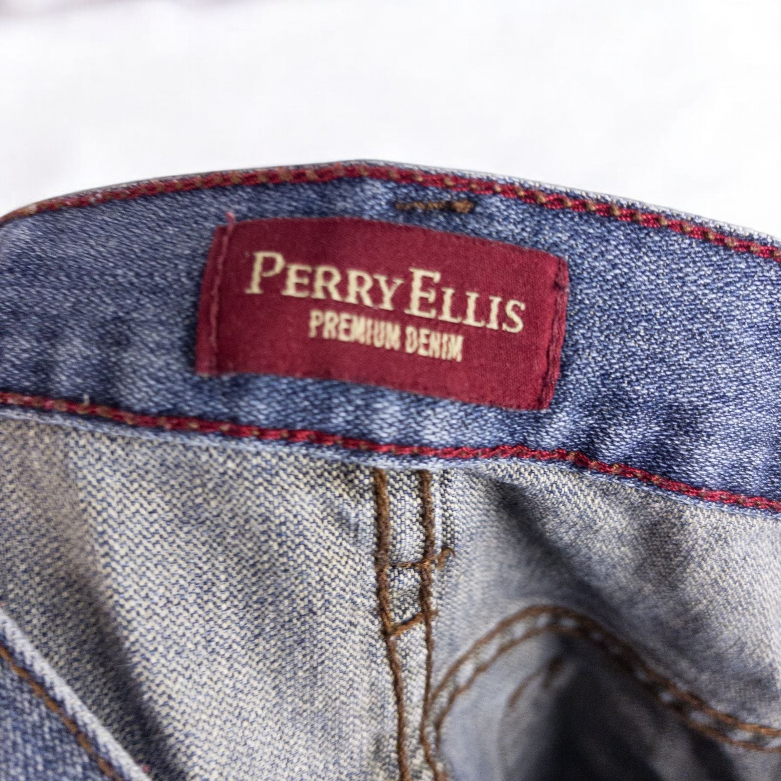 Perry Ellis women's blue denim jeans with five pockets hanging on a hanger front and back views image 10