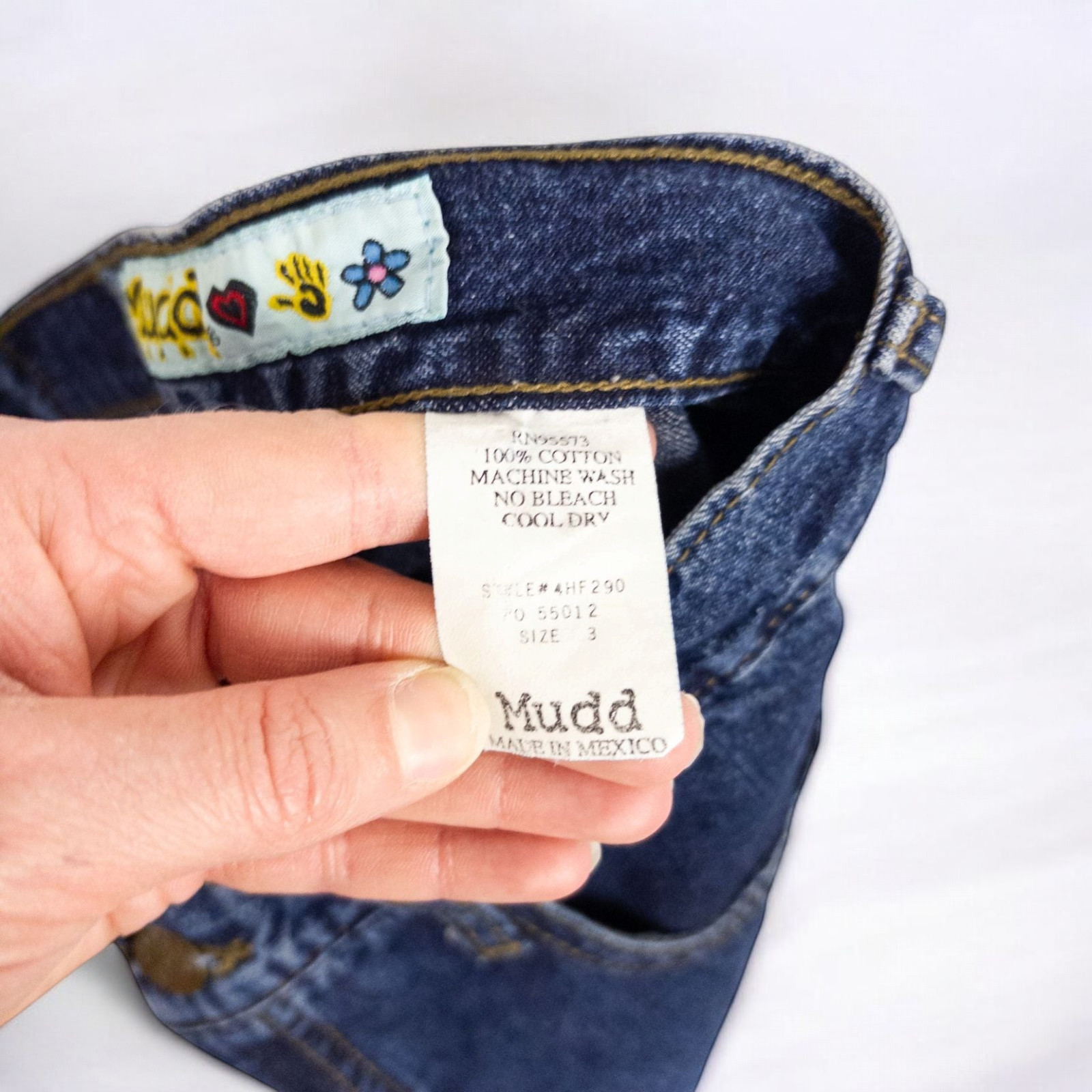 Vintage 1990s Mudd blue denim jeans with button closure hanging on hanger front view image 9