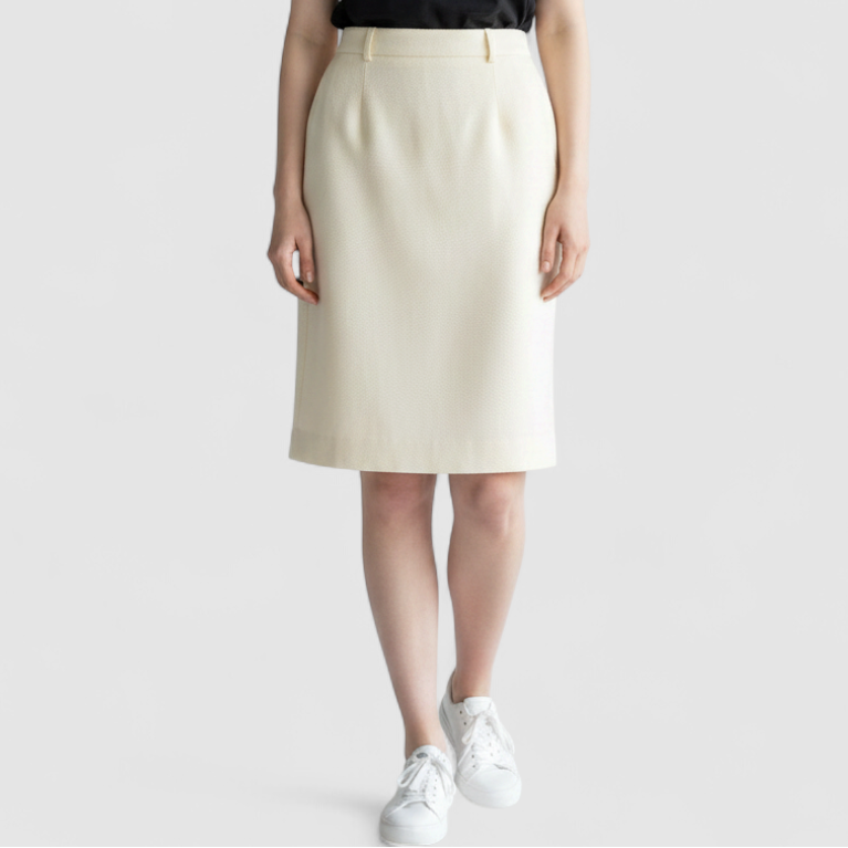 Vintage ivory pique pencil skirt with side zipper and button tab detail hanging on a hanger on model