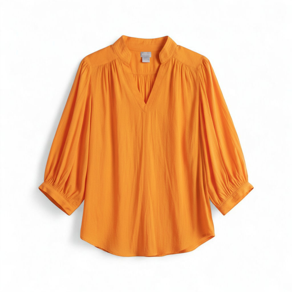 Bright orange long sleeve tunic blouse by Chicos hanging on a white hanger, showing front, back, sleeves, and fabric texture with small pinprick flaw front on white muslin photography backdrop