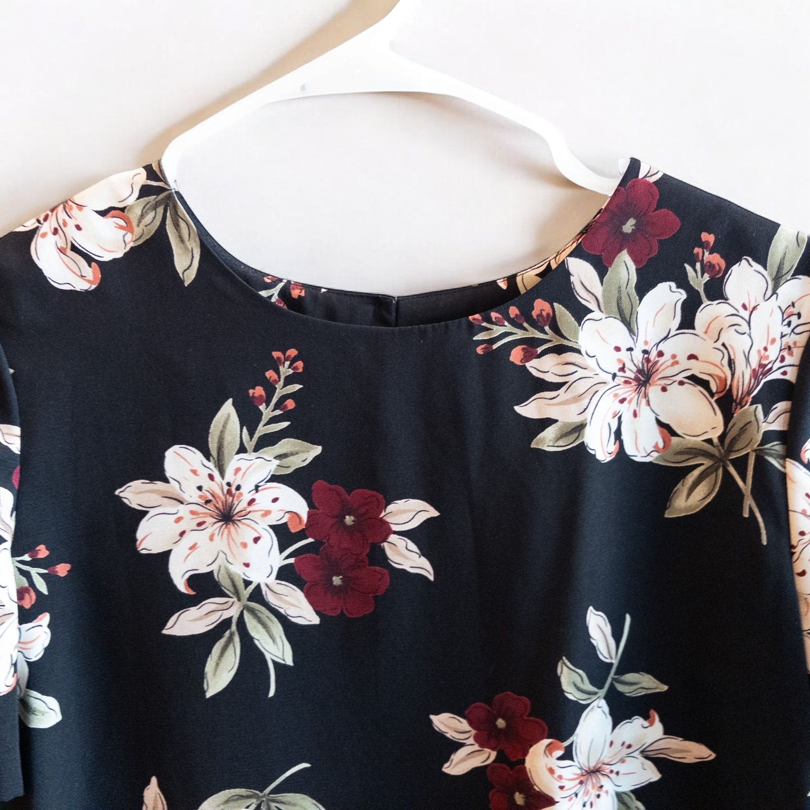 Jaclyn Smith vintage black floral blouse hanging on white hanger with white door background image 2
