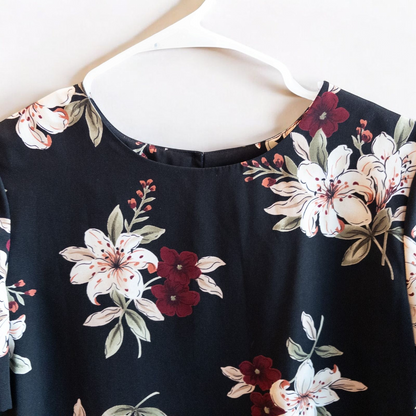 Jaclyn Smith vintage black floral blouse hanging on white hanger with white door background image 2