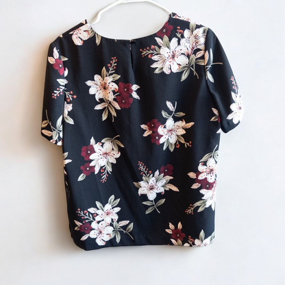 Jaclyn Smith vintage black floral blouse hanging on white hanger with white door background image 4