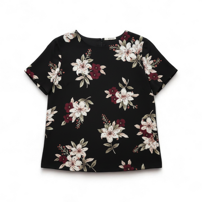 Jaclyn Smith vintage black floral blouse hanging on white hanger with white door background front on white muslin photography backdrop