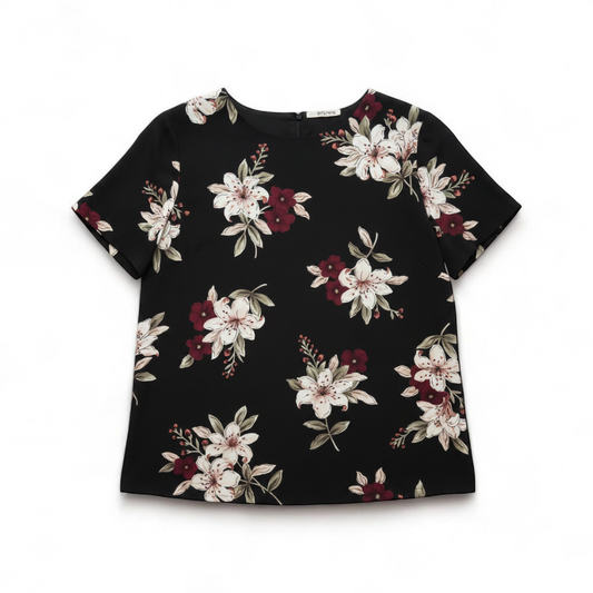 Jaclyn Smith vintage black floral blouse hanging on white hanger with white door background front on white muslin photography backdrop