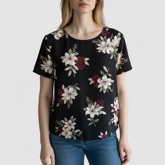 Jaclyn Smith vintage black floral blouse hanging on white hanger with white door background on model