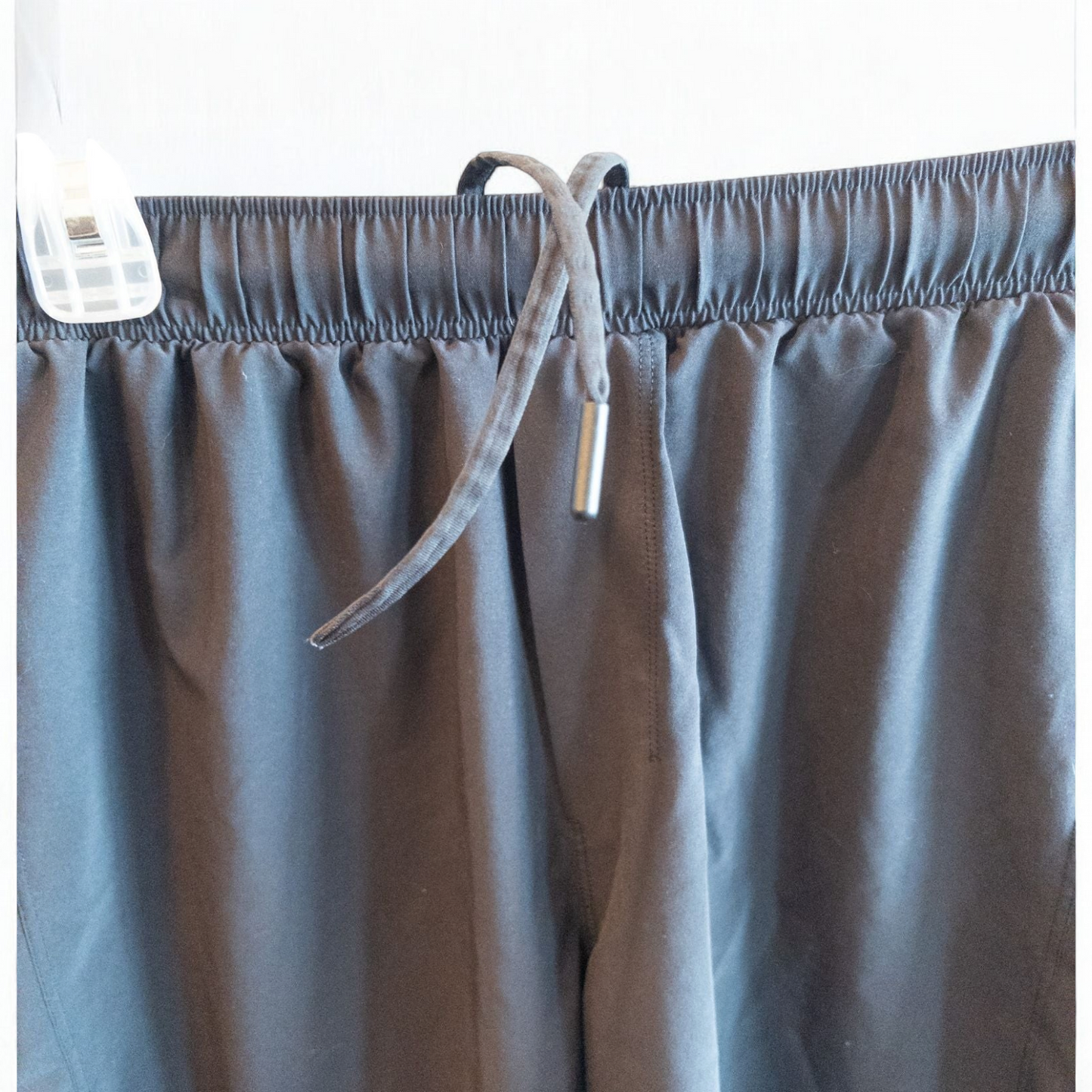 Black lululemon men's lightweight athletic shorts with elastic waistband and drawstring tie hanging on clips image 2