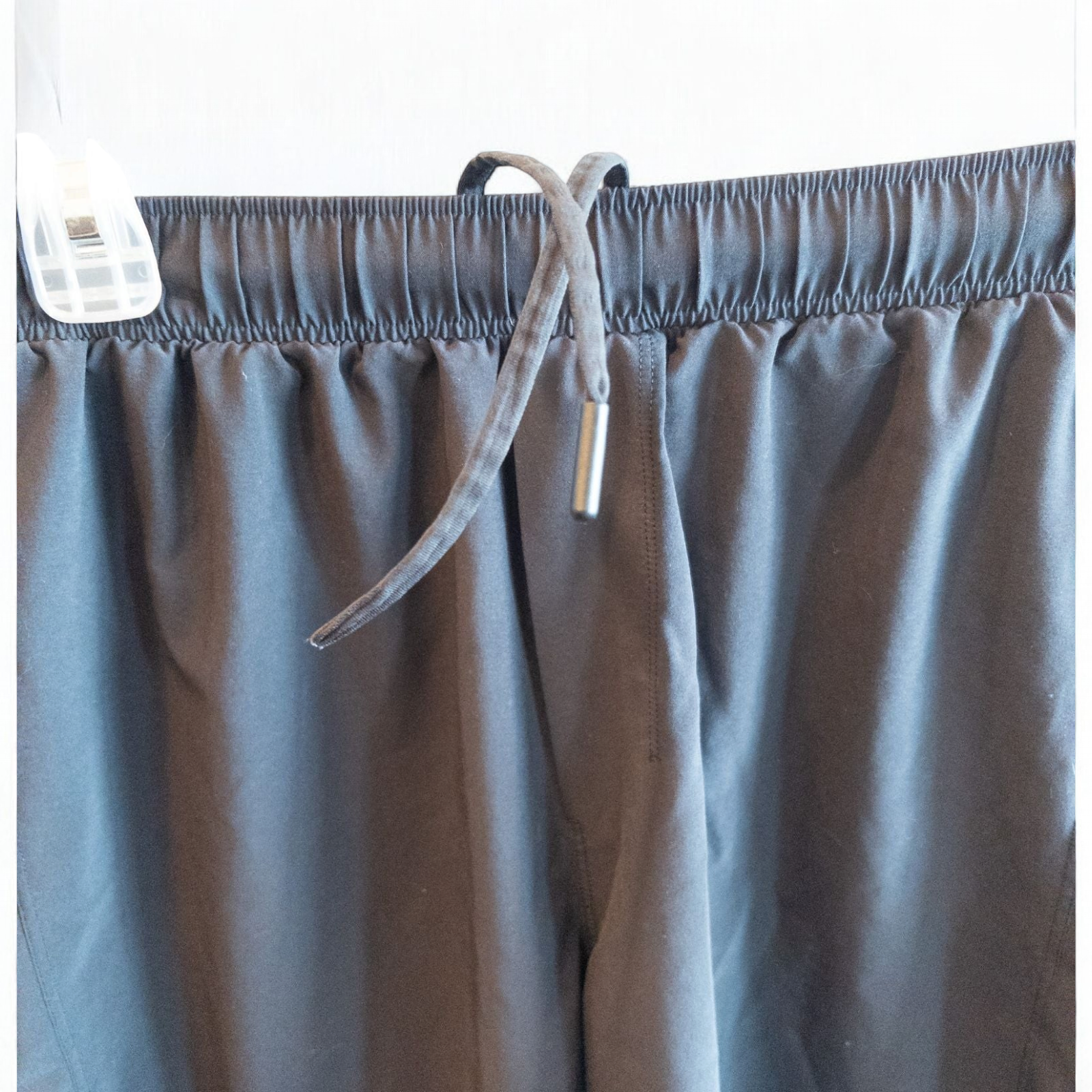 Black lululemon men's lightweight athletic shorts with elastic waistband and drawstring tie hanging on clips image 2
