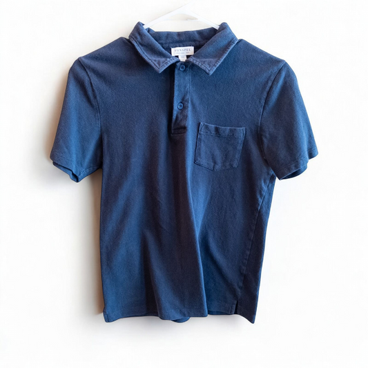 Blue Sunspel cotton polo shirt with short sleeves and chest pocket hanging on white hanger