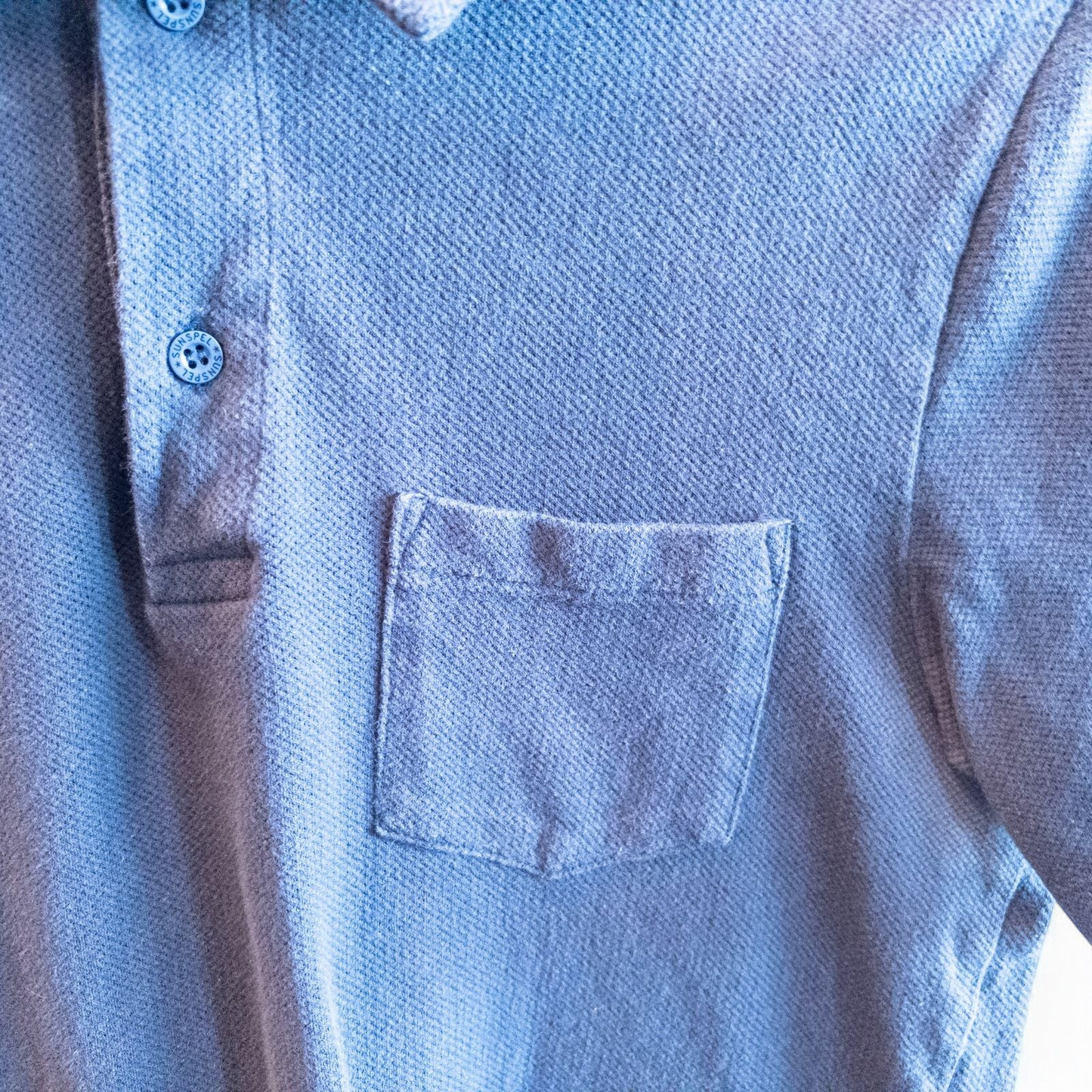 Blue Sunspel cotton polo shirt with short sleeves and chest pocket hanging on white hanger image 3