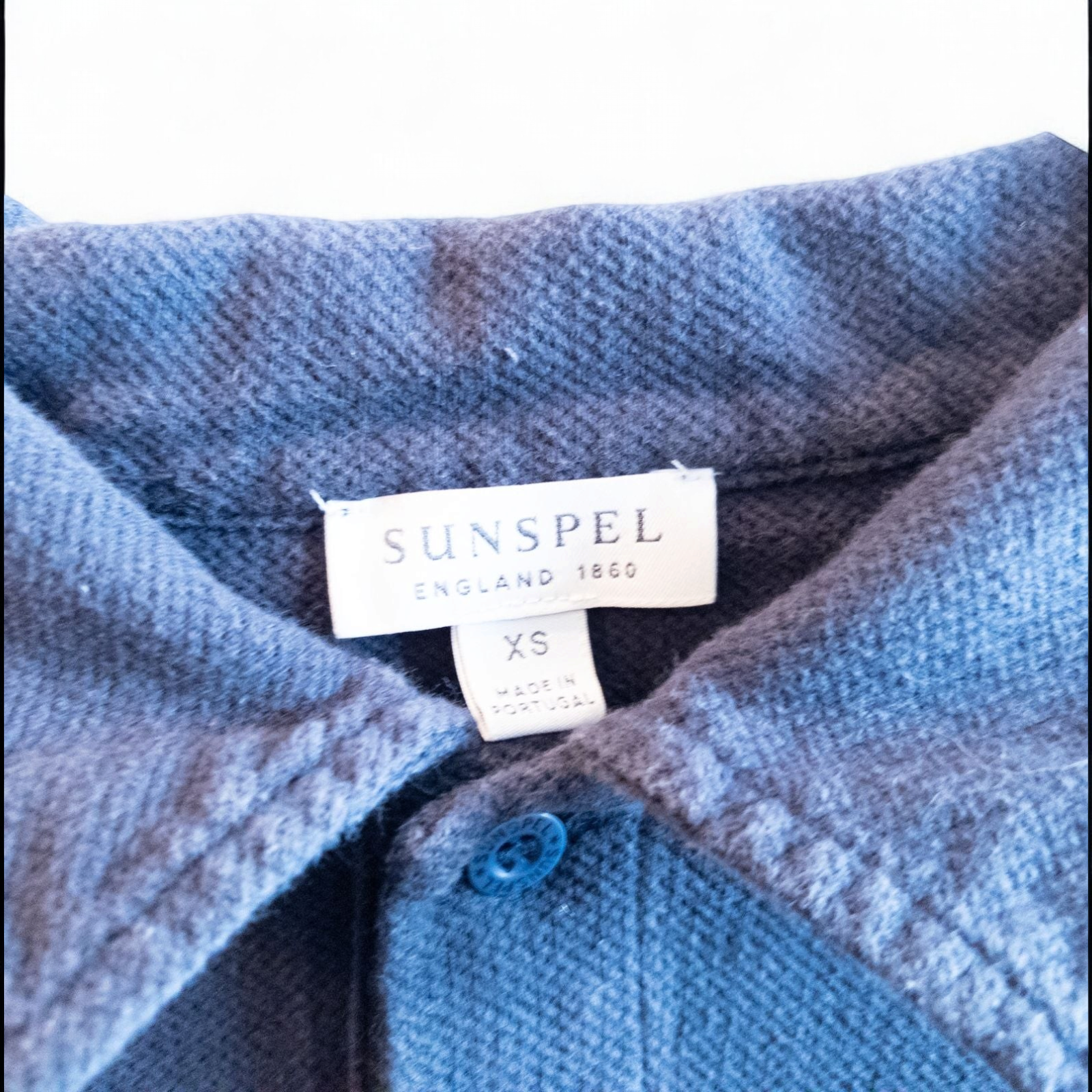 Blue Sunspel cotton polo shirt with short sleeves and chest pocket hanging on white hanger image 6