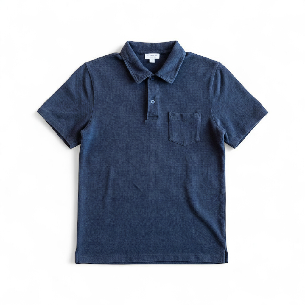 Blue Sunspel cotton polo shirt with short sleeves and chest pocket hanging on white hanger front on white muslin photography backdrop