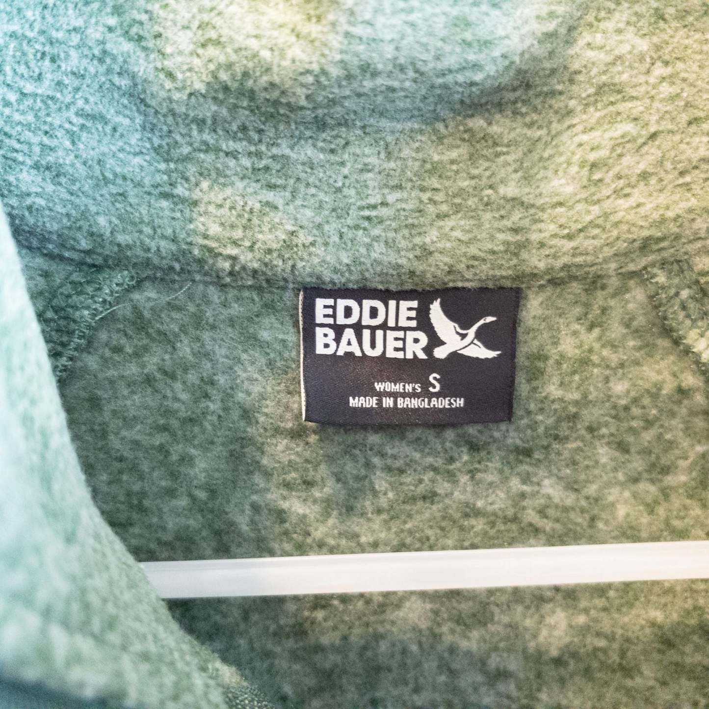 Eddie Bauer green quarter zip sweatshirt hanging on a plastic hanger showing front, back, collar, and inside label image 6