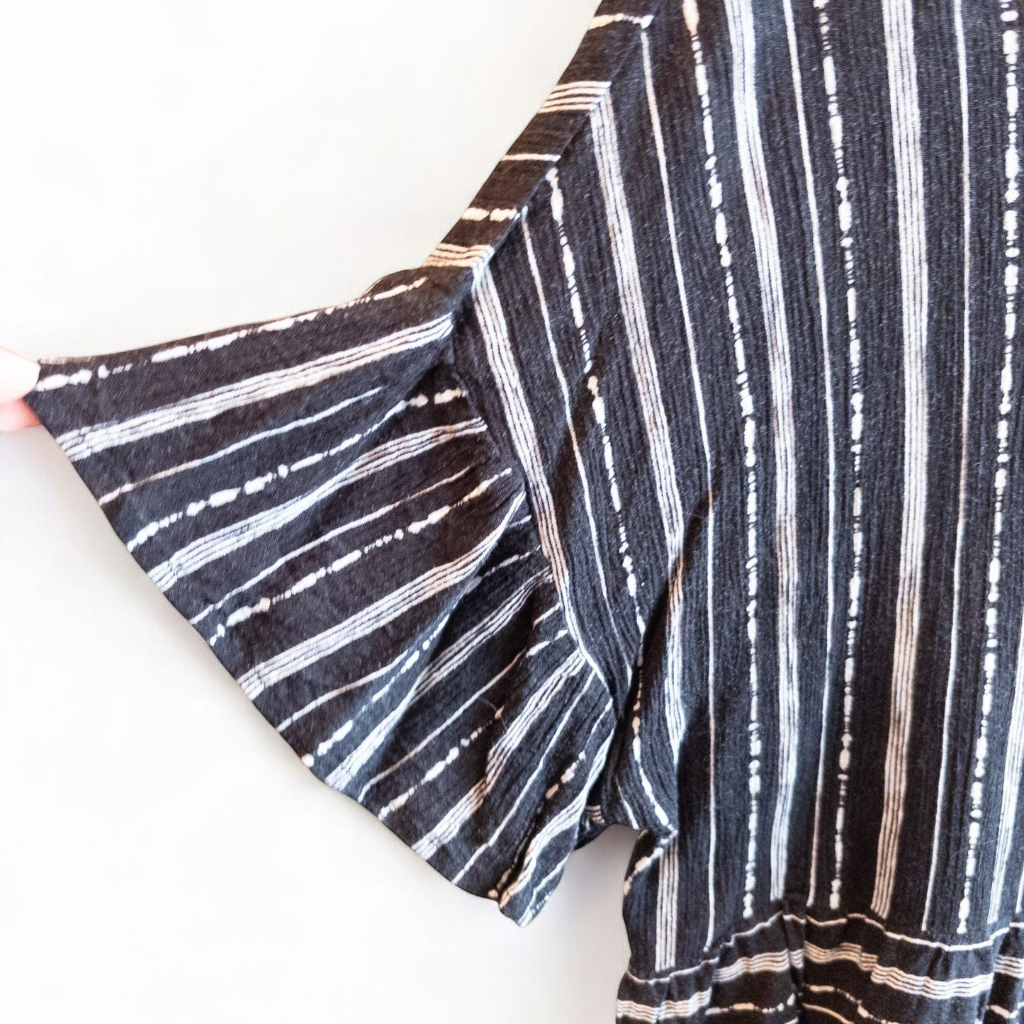 Paper Crane black and white striped peplum blouse with round neck and flutter sleeves hanging on white door image 2