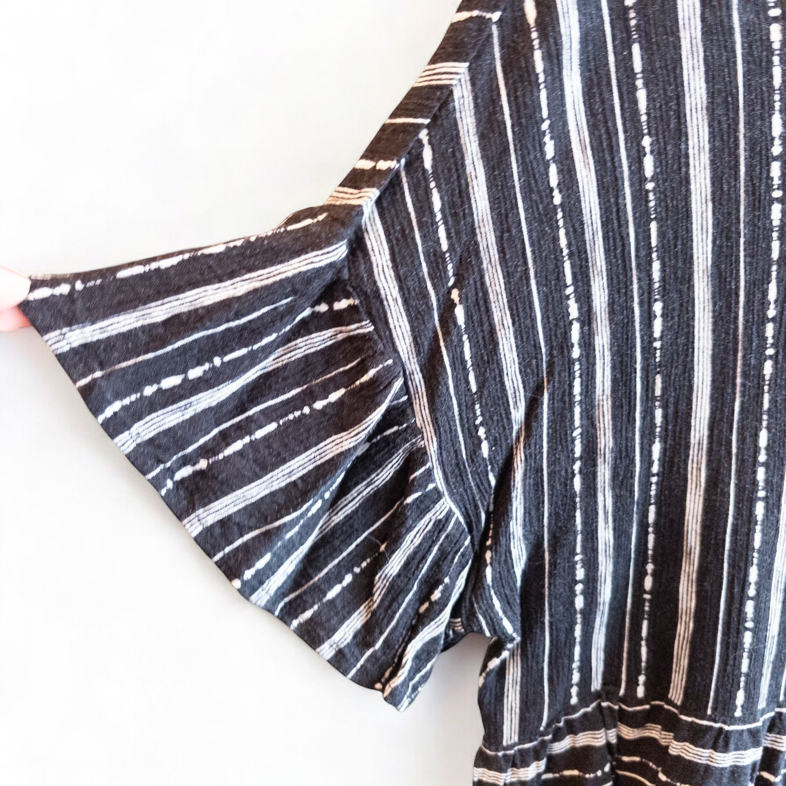 Paper Crane black and white striped peplum blouse with round neck and flutter sleeves hanging on white door image 2