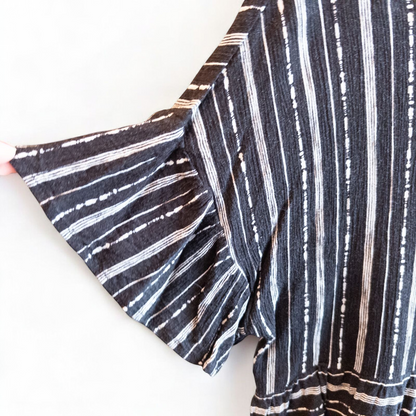 Paper Crane black and white striped peplum blouse with round neck and flutter sleeves hanging on white door image 2