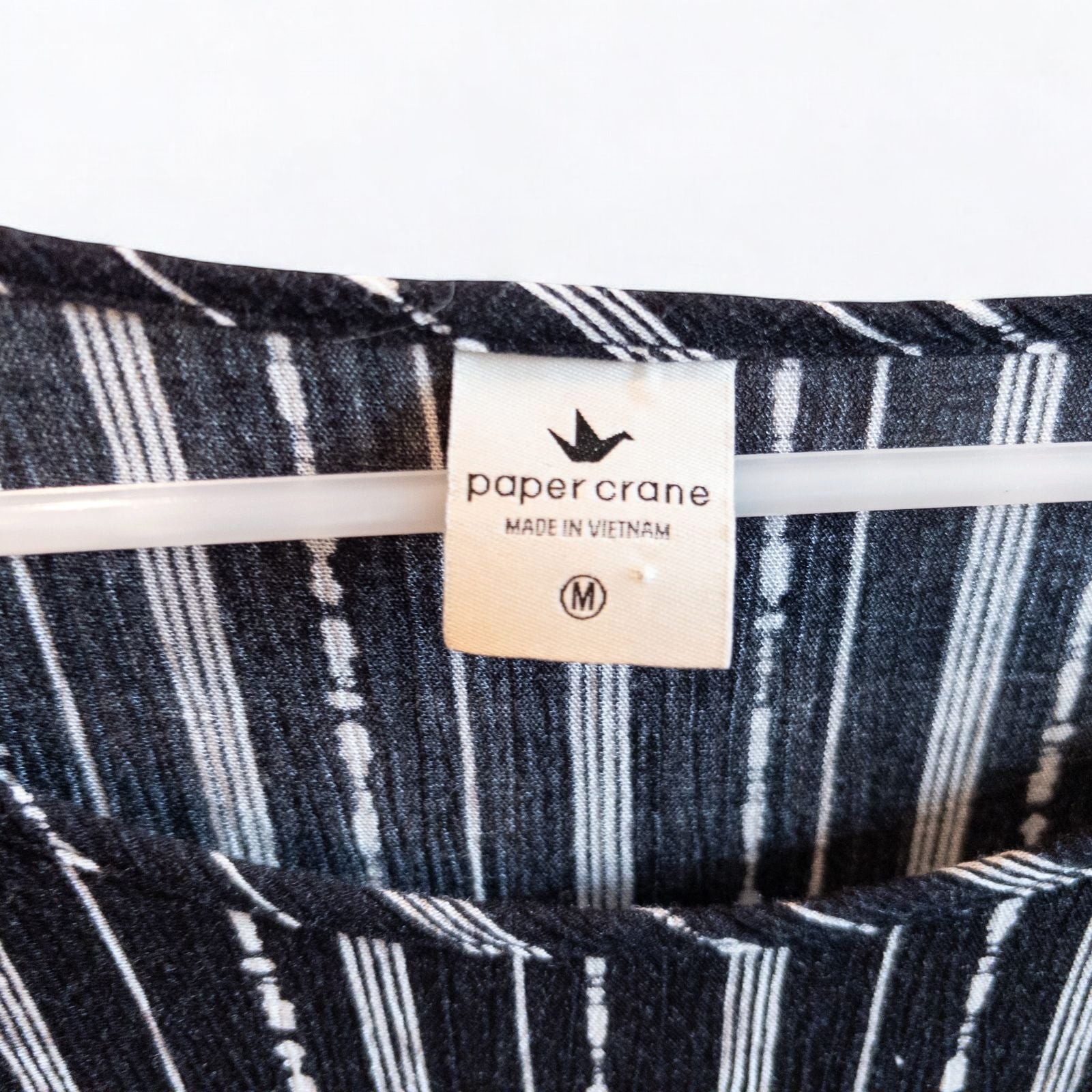 Paper Crane black and white striped peplum blouse with round neck and flutter sleeves hanging on white door image 5