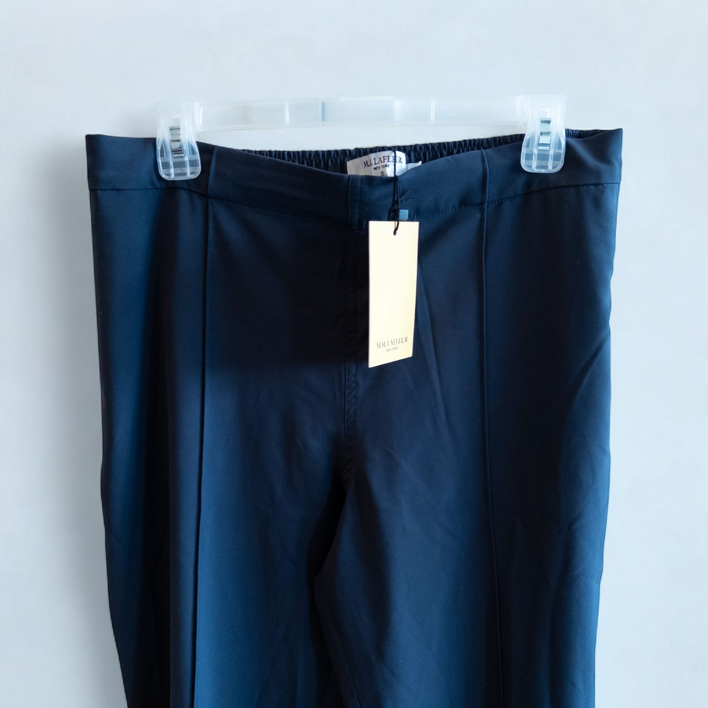 Gray MM LaFleur tech pants hanging on a hanger front and back views with close up of waistband, zipper, and label image 3