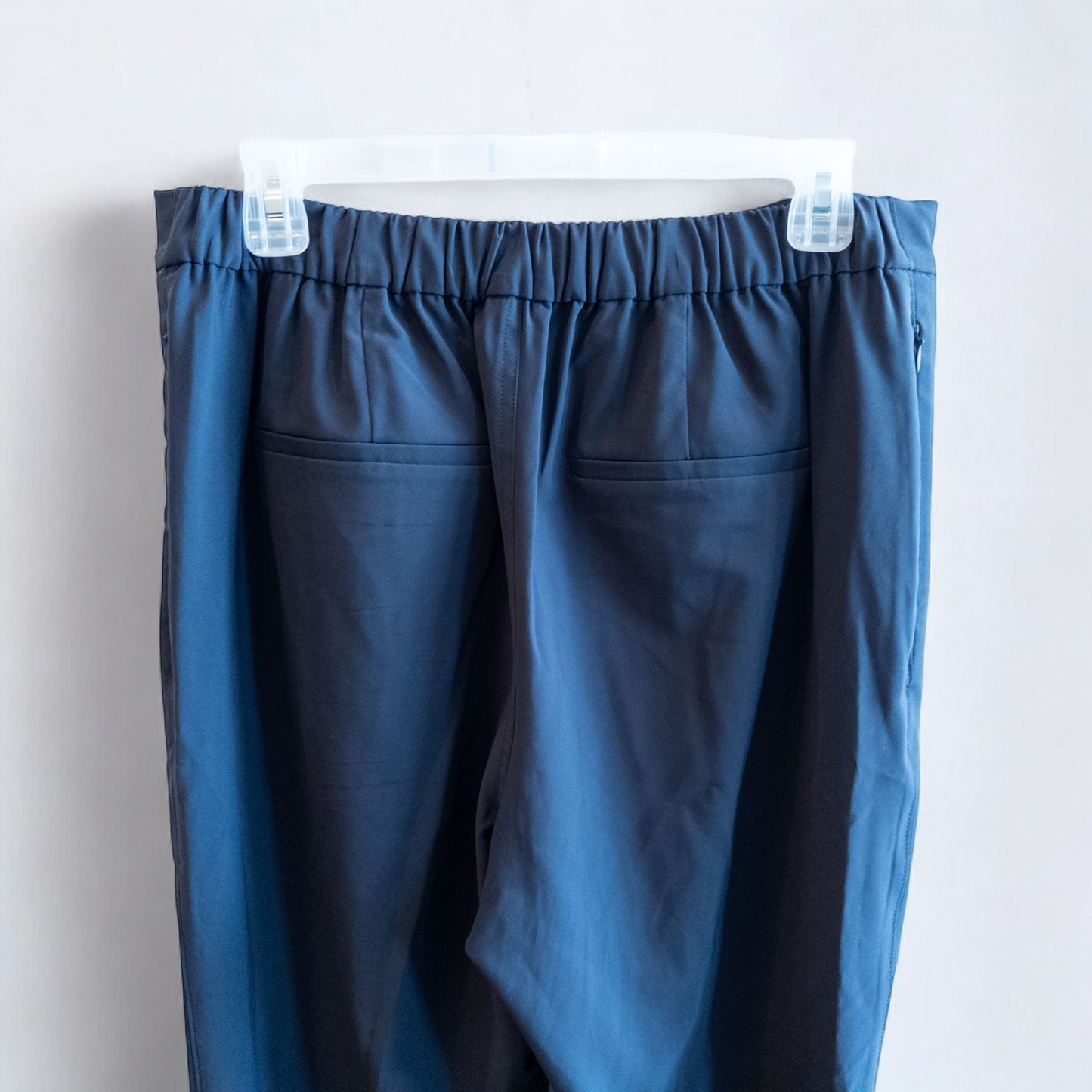 Gray MM LaFleur tech pants hanging on a hanger front and back views with close up of waistband, zipper, and label image 7