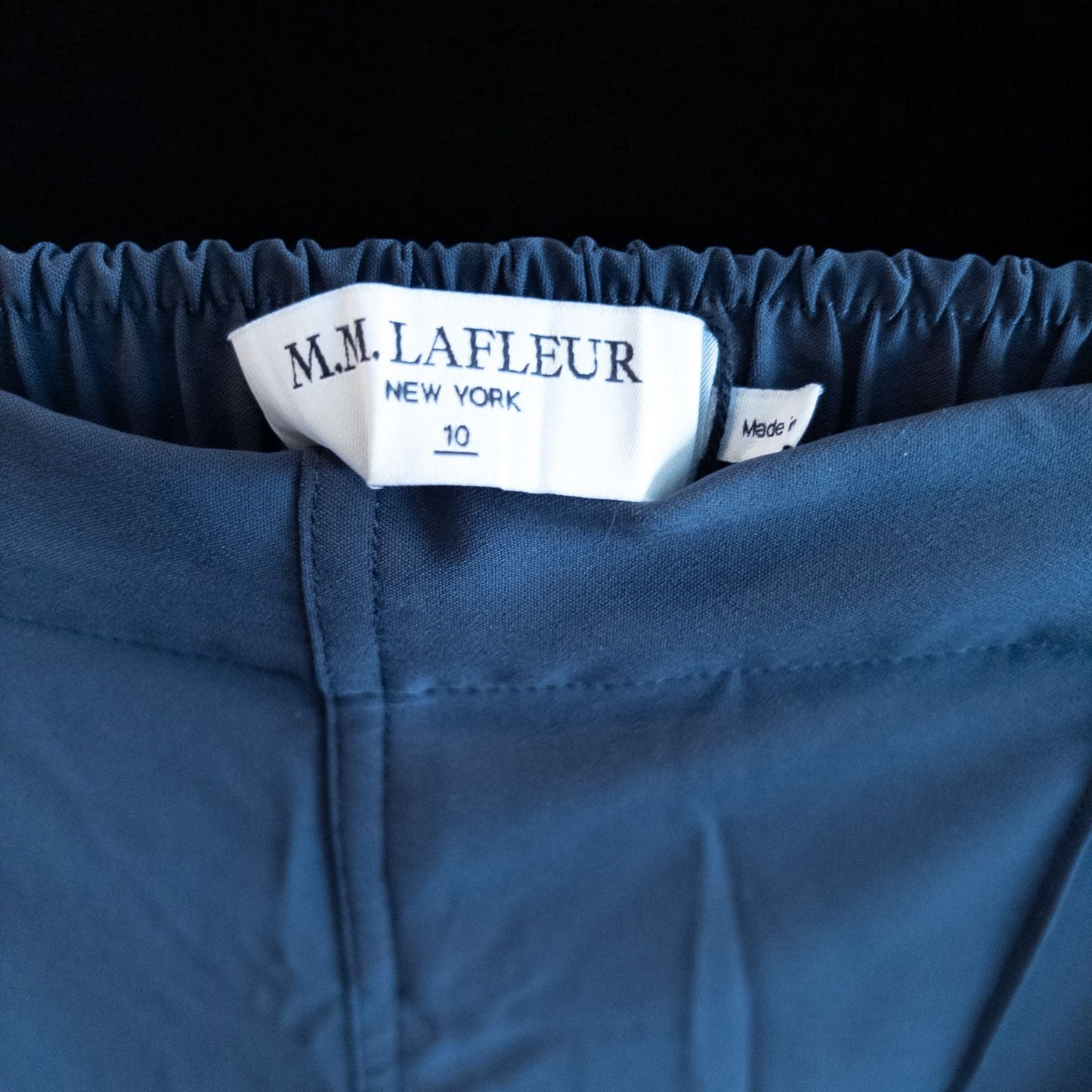 Gray MM LaFleur tech pants hanging on a hanger front and back views with close up of waistband, zipper, and label image 8