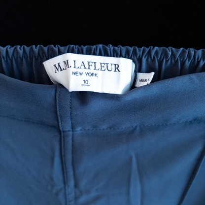 Gray MM LaFleur tech pants hanging on a hanger front and back views with close up of waistband, zipper, and label image 8