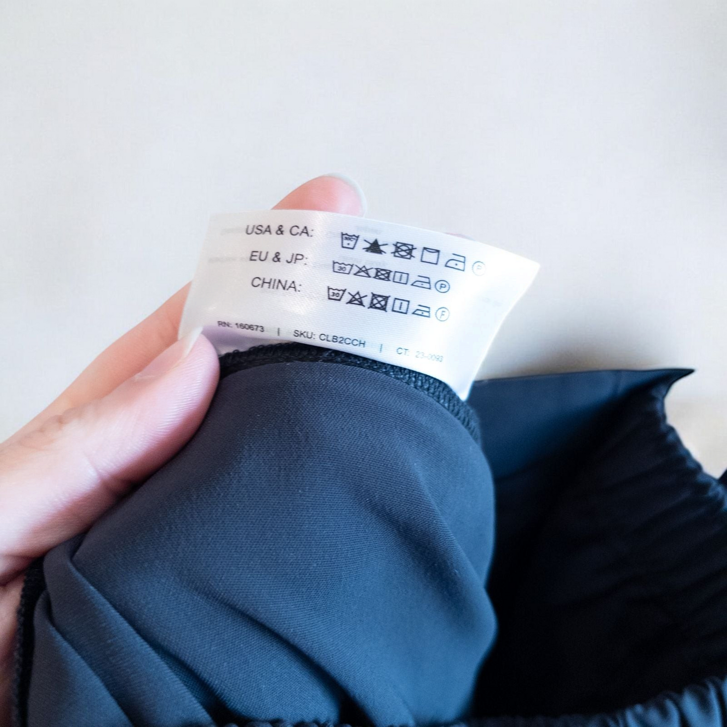 Gray MM LaFleur tech pants hanging on a hanger front and back views with close up of waistband, zipper, and label image 9