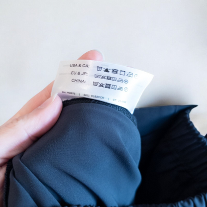 Gray MM LaFleur tech pants hanging on a hanger front and back views with close up of waistband, zipper, and label image 9