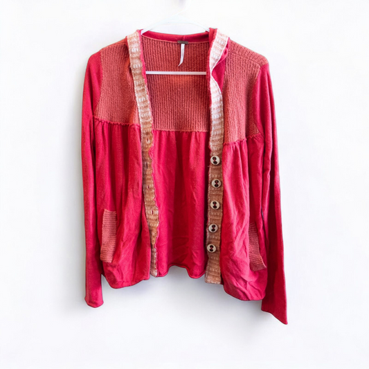 Free People red wool knit cardigan sweater with hood and button front, hung on white hanger