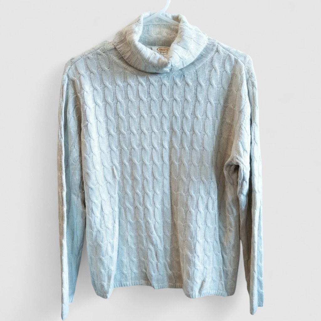 Tan cable knit Talbots turtleneck sweater with silk cashmere blend hanging on a white hanger on model