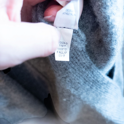 Athleta gray wool cashmere open knit sweater cardigan hanging on white door with two front pockets and ribbed cuffs, showing small brown speck on pocket and fuzzy texture image 12