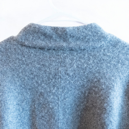 Athleta gray wool cashmere open knit sweater cardigan hanging on white door with two front pockets and ribbed cuffs, showing small brown speck on pocket and fuzzy texture image 8