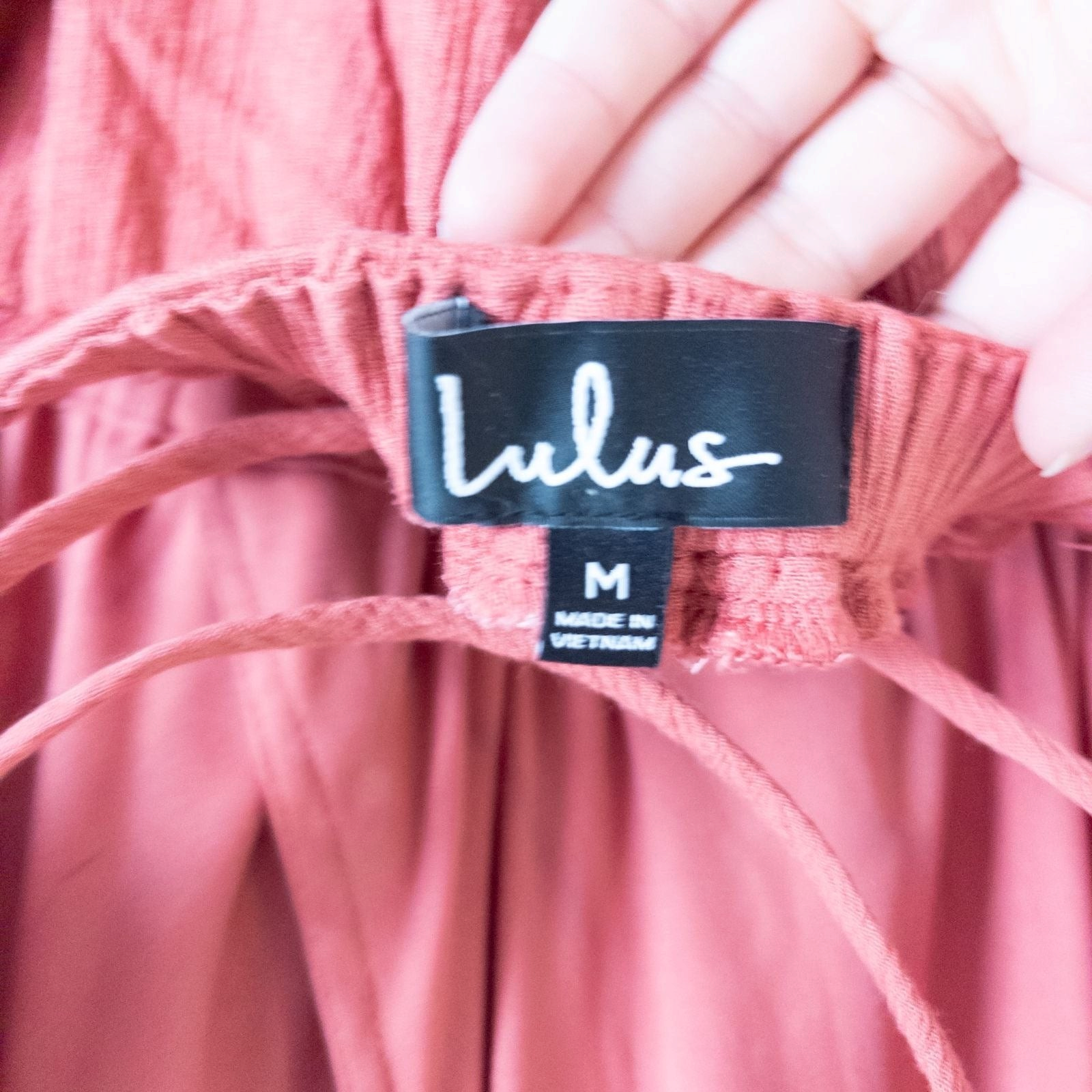Pink sleeveless maxi dress with v-neckline and open back hanging on plastic hanger in front of mirror image 11