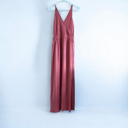 Pink sleeveless maxi dress with v-neckline and open back hanging on plastic hanger in front of mirror image 2