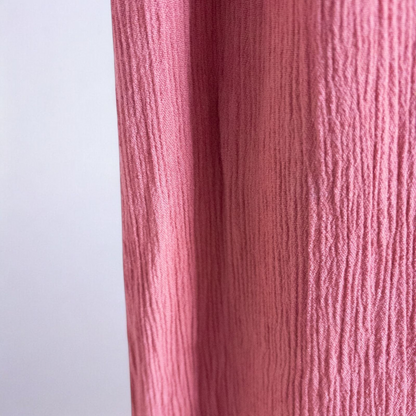 Pink sleeveless maxi dress with v-neckline and open back hanging on plastic hanger in front of mirror image 5
