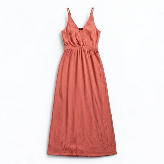 Pink sleeveless maxi dress with v-neckline and open back hanging on plastic hanger in front of mirror front on white muslin photography backdrop
