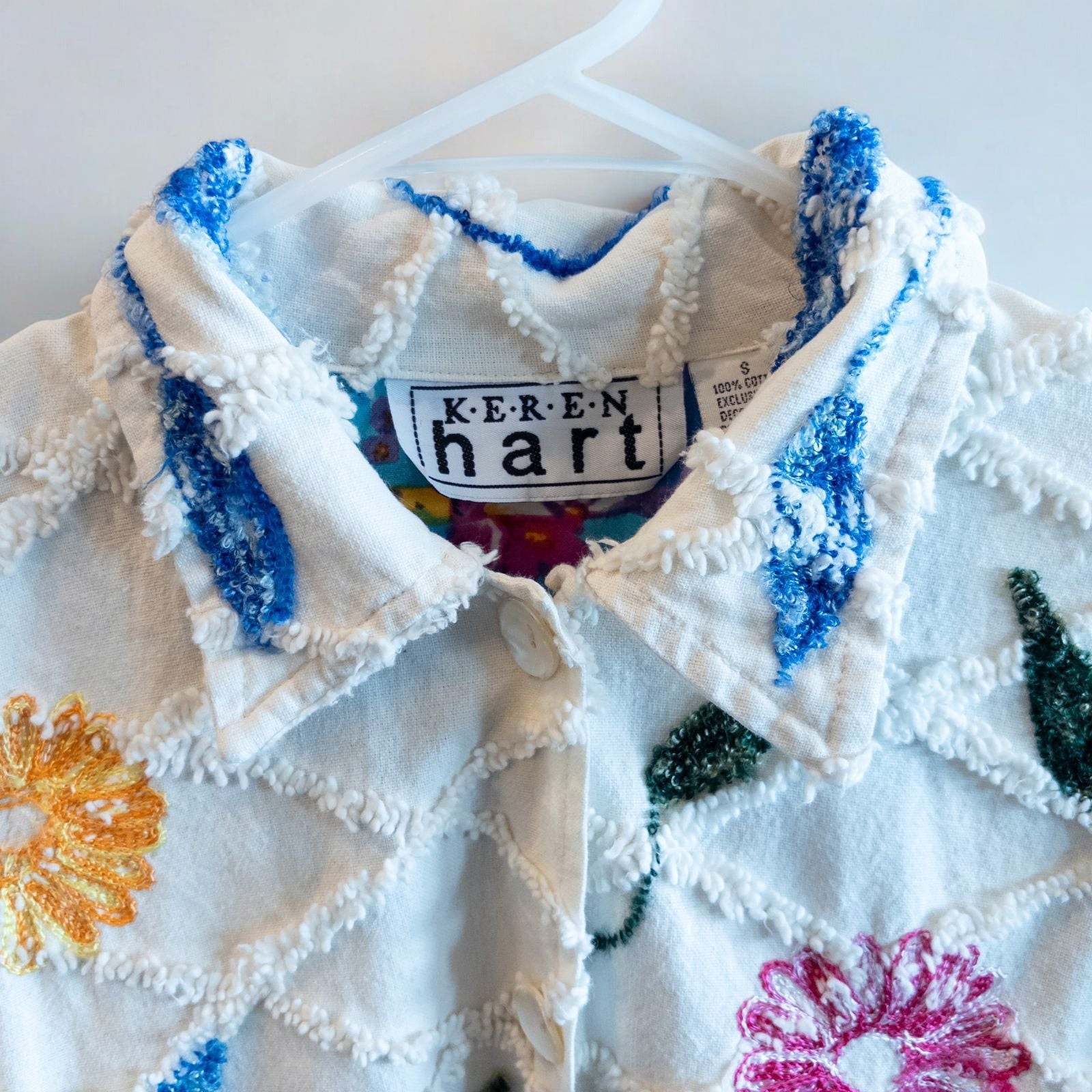 Keren Hart vintage embroidered flower jacket in white with multicolor floral embroidery on a woman and hanging on hangers image 5