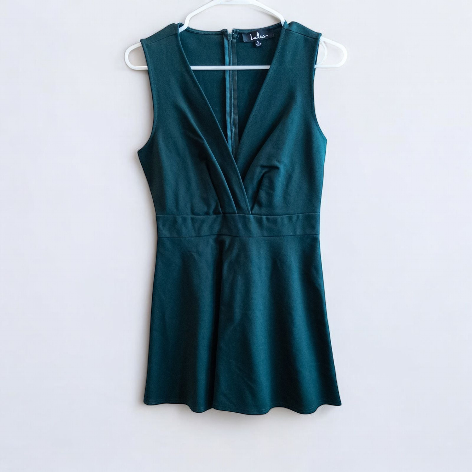 Lulus green sleeveless mini dress with deep v-neck and back zipper hanging on white hanger