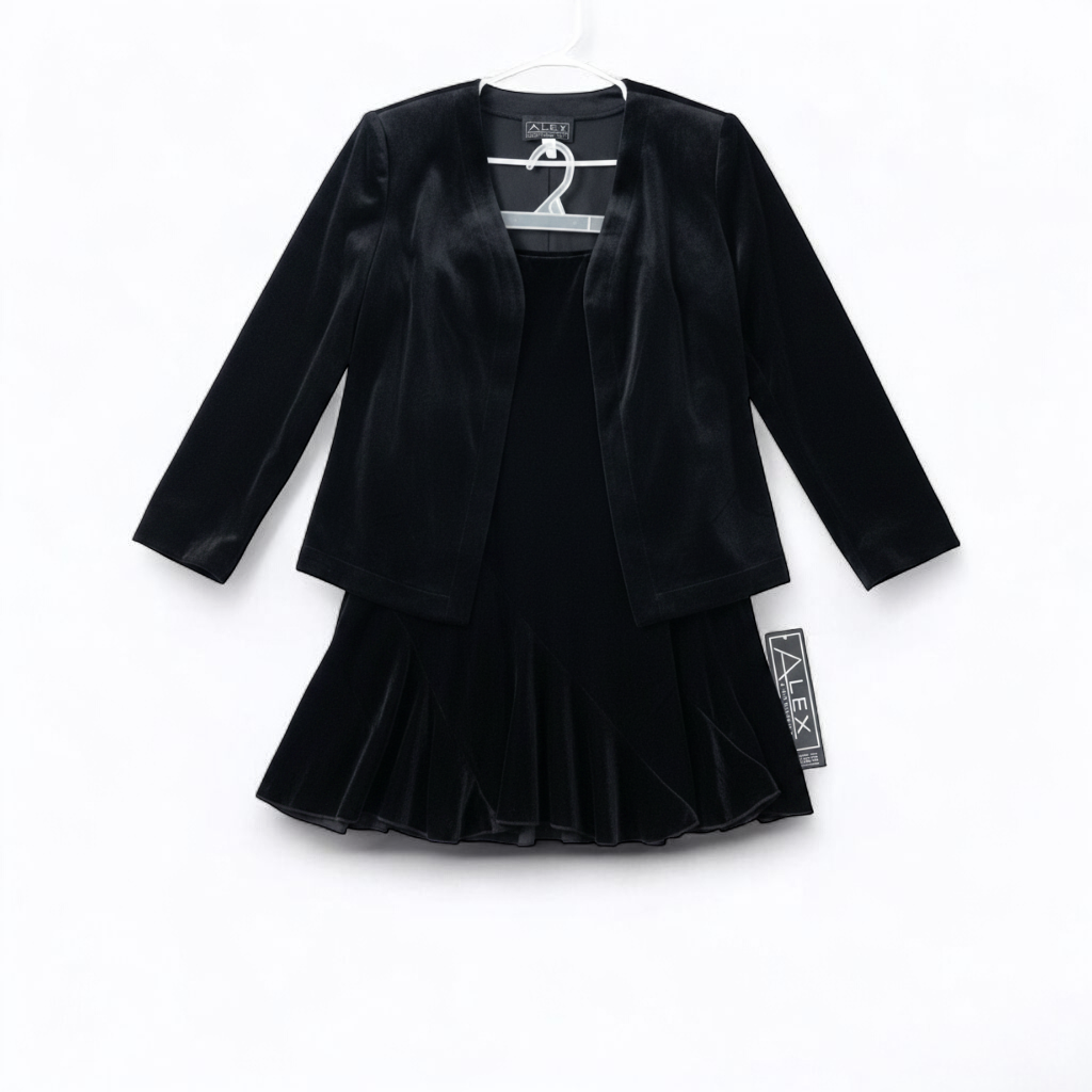 Alex black velvet jacket and skirt set hanging on hanger, showing classic fitted jacket with padded shoulders and flared skirt. front on white muslin photography backdrop