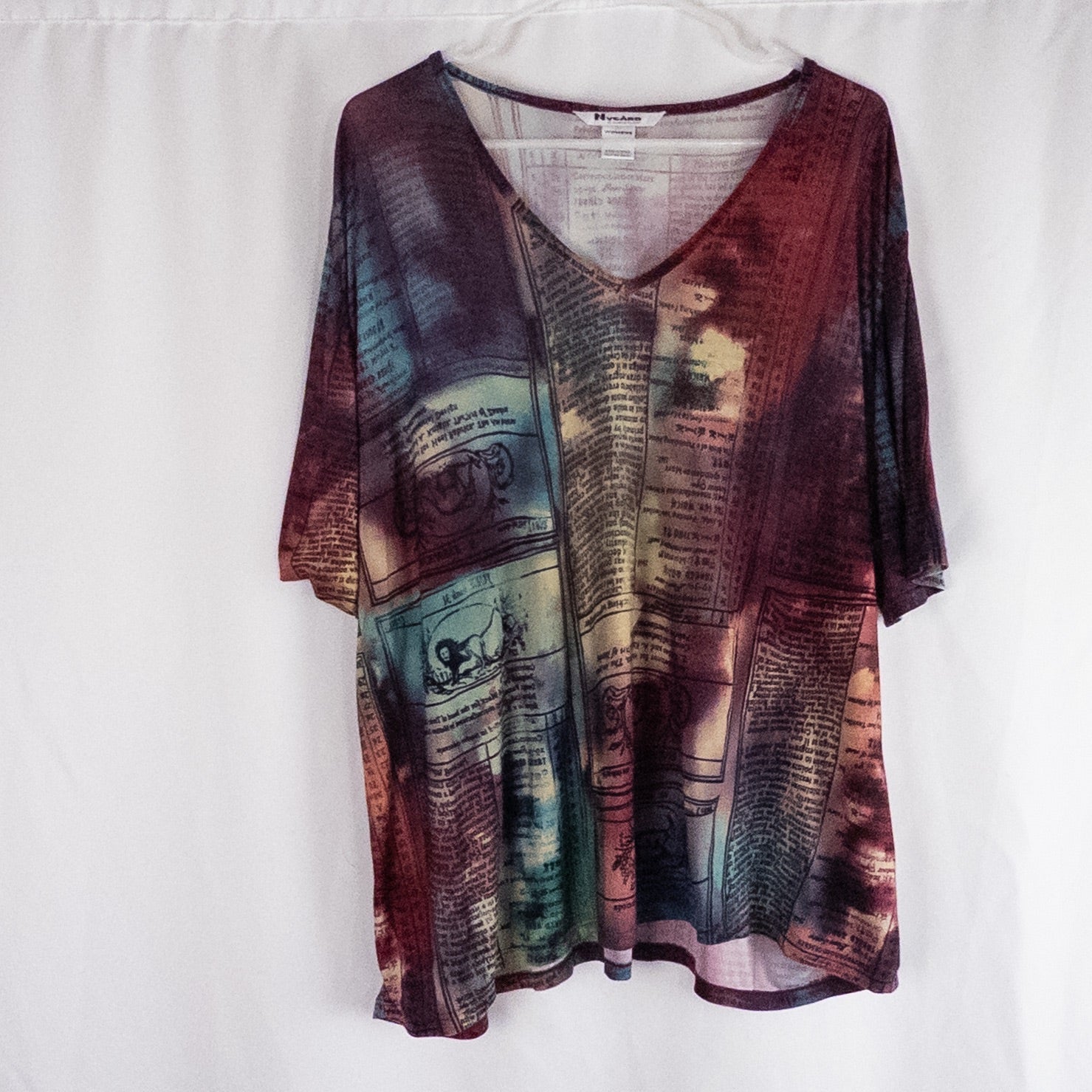 Nygard multicolor horoscope boho top with v-neck and short sleeves hanging on plastic hanger