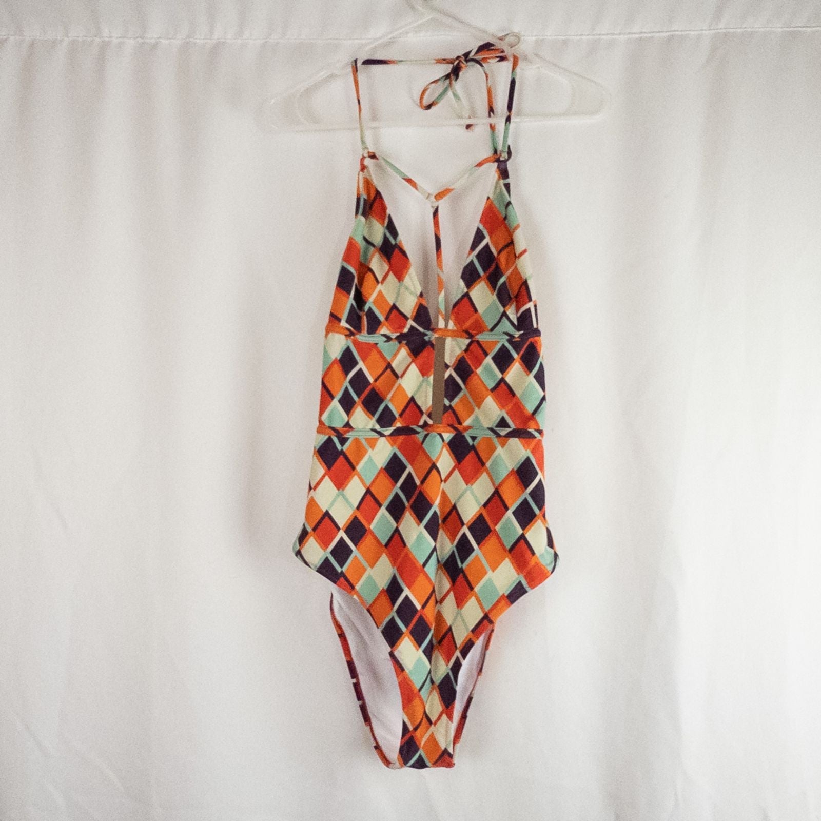 Orange teal geometric diamond pattern Cupshe one-piece swimsuit with halter neck and cutout detail shown hanging on white hanger