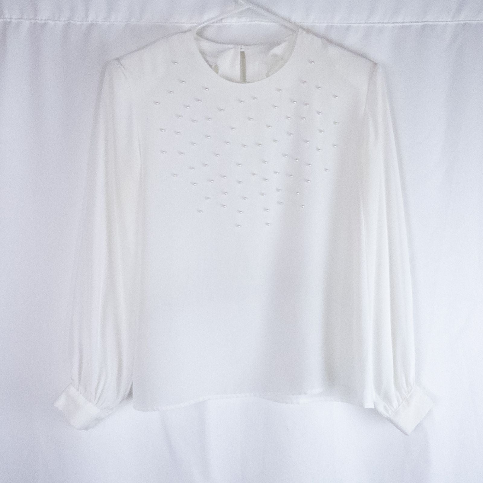 Anne Kriste vintage white sheer blouse with pearl beading on front and long sleeves with button cuffs hanging on hanger
