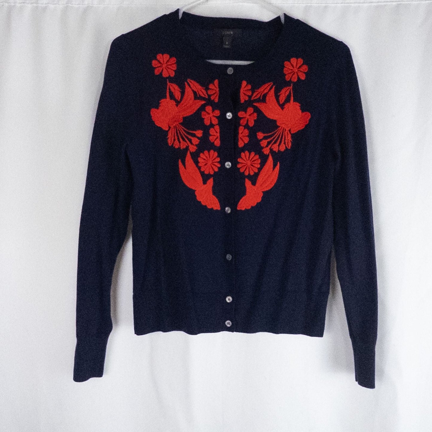 J Crew navy blue cardigan sweater with red embroidered floral design on front, button closure, long sleeves, and crew neck.