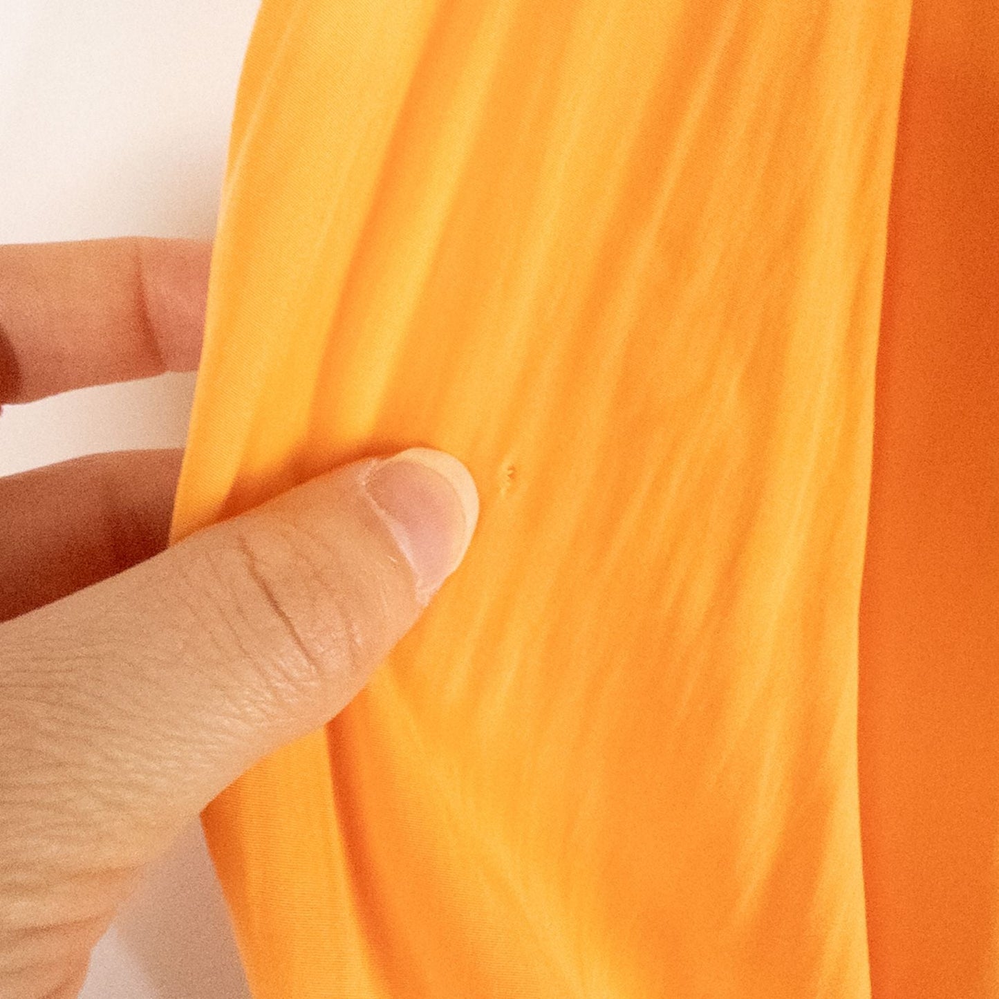 Bright orange long sleeve tunic blouse by Chicos hanging on a white hanger, showing front, back, sleeves, and fabric texture with small pinprick flaw image 3