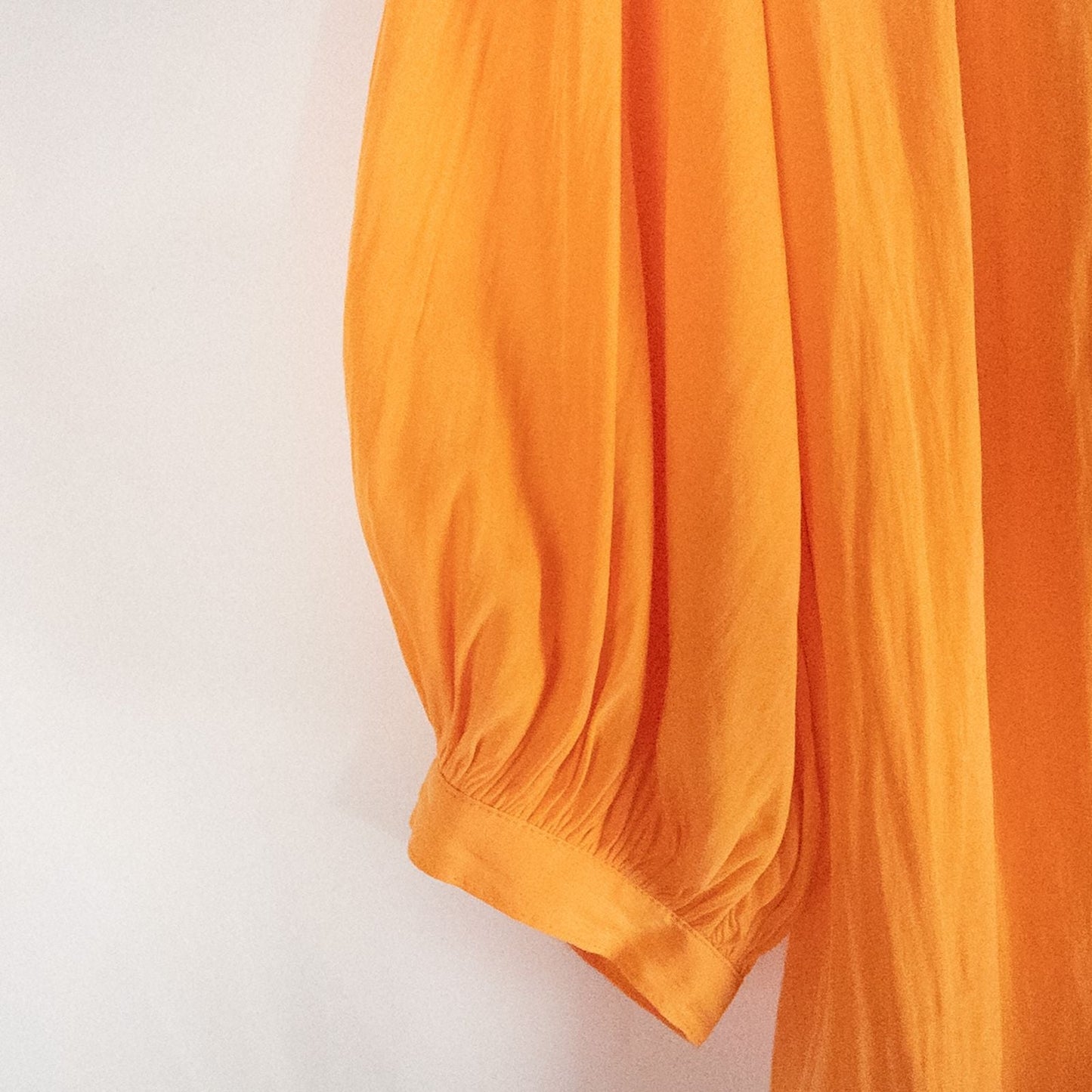 Bright orange long sleeve tunic blouse by Chicos hanging on a white hanger, showing front, back, sleeves, and fabric texture with small pinprick flaw image 2